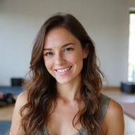 Bild einer jungen Frau, die glücklich und entspannt in einem Yoga-Studio lächelt.